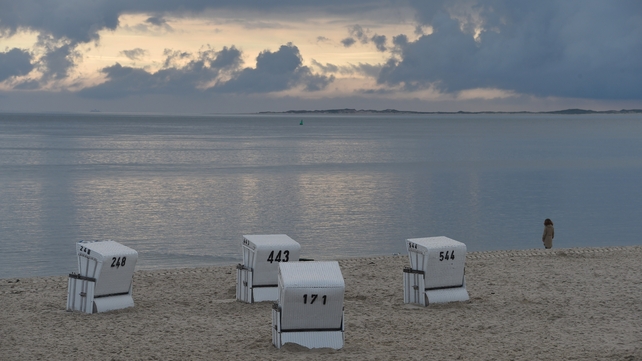 A woman stands at the North Sea beach of Hoernum in northwest Germany