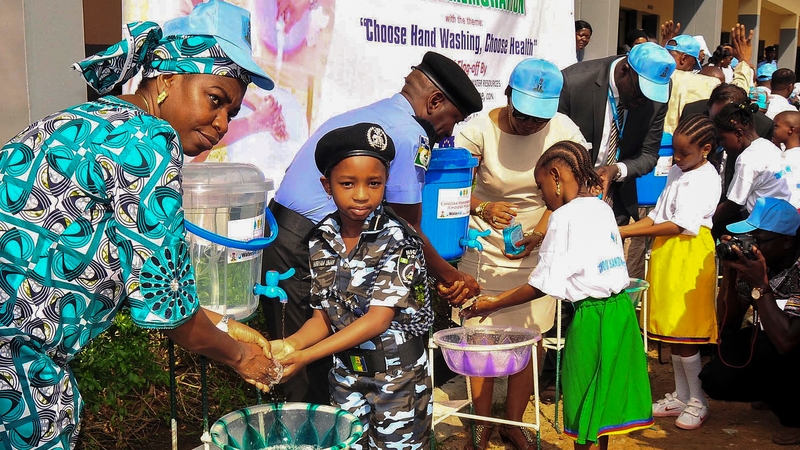 The Nigerian Minister of Water Resources washes hands with school children as part of an Ebola campaign