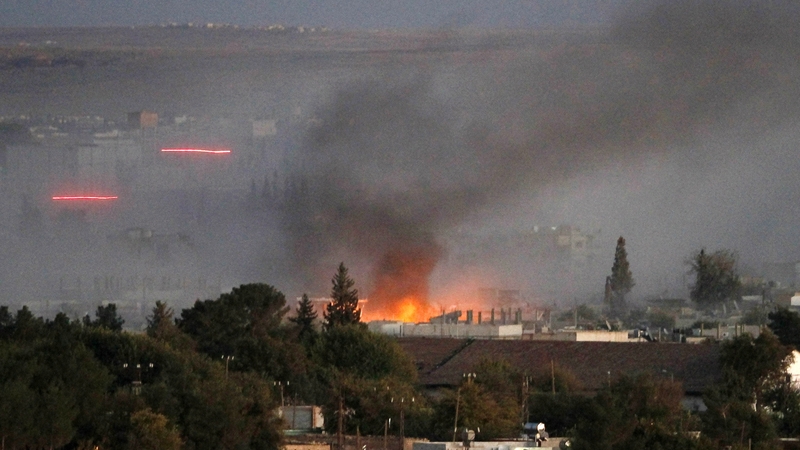 Smoke rises as bullets with tracers fly through the air after an explosion rocks Syrian city of Kobane