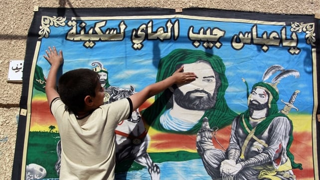 An Iraqi with banner of Imam Hussein displayed in a street ahead of Ashura
