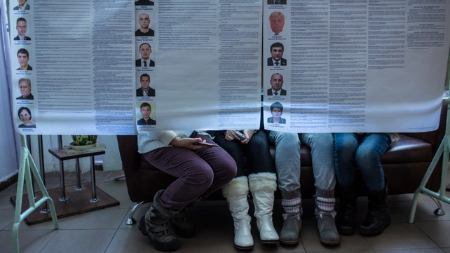 Children sit behind informational posters showing the various candidates for Ukraine's parliament