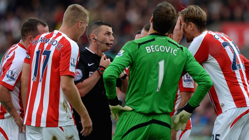 Stoke City players surround referee Michael Oliver after he awarded a penalty to Swansea