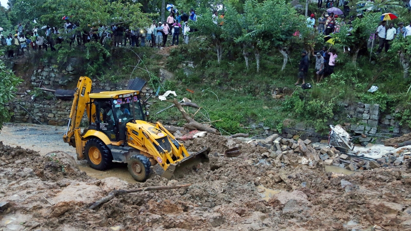 The landslide area being excavated by a bulldozer as people watch during the rescue operation