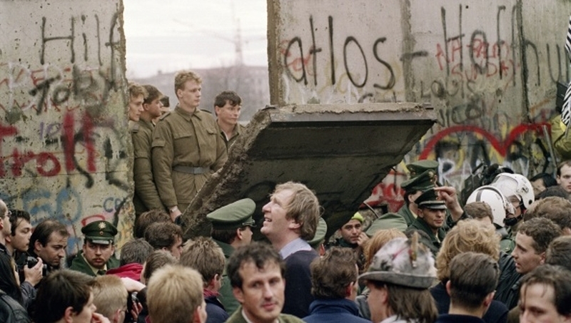 East German border guards stand at a broken section of the wall in 1989