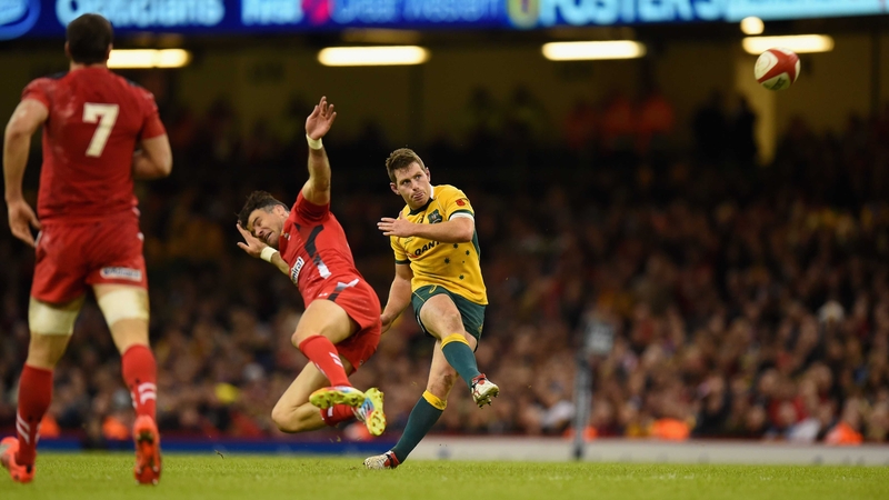 Australia's Bernard Foley slots over a drop-goal despite the efforts of Wales scrum-half Mike Phillips