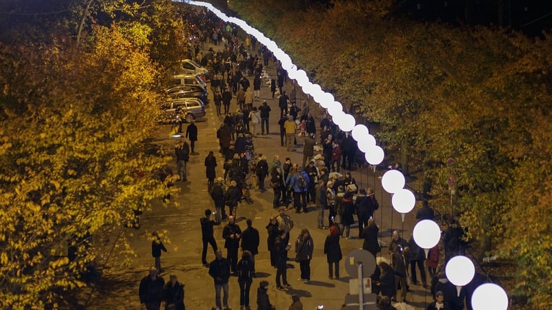 Visitors walk under a light installation of balloons tethered to lamps along the course of the former Berlin Wal