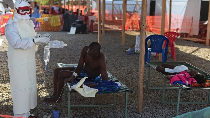 A nurse wearing personal protective equipment helps an Ebola patient at the Kenama treatment centre in Sierra Leone