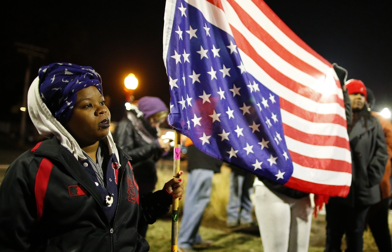 A protester holds an American flag outside the Ferguson Police Station