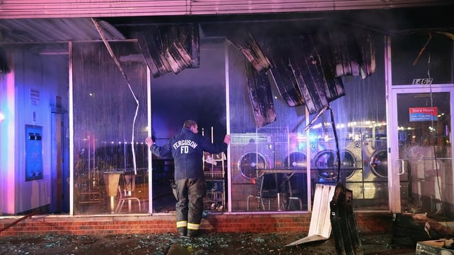 A Ferguson firefighter surveys the damage to a launderette after rioting subsided