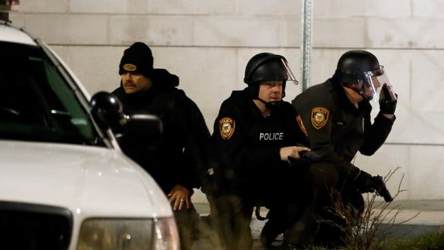 Police officials in riot gear take positions outside the Ferguson Police department