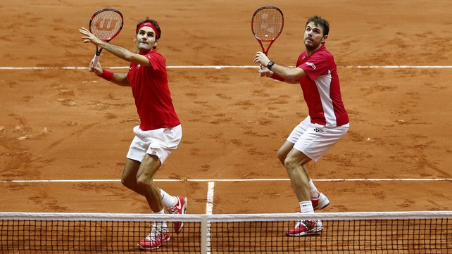 Roger Federer and Stan Wawrinka both prepare to execute a smash during Switzerland's win over France in their double match at the Davis Cup