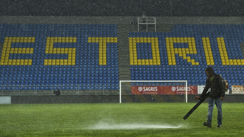 A stadium employee tries to remove water from the pitch in Estoril, Portugal