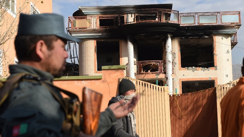 Afghan police stand outside the compound where four people died during Taliban attack