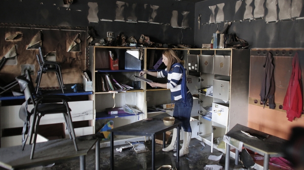 A woman inspects the damage inside the classroom