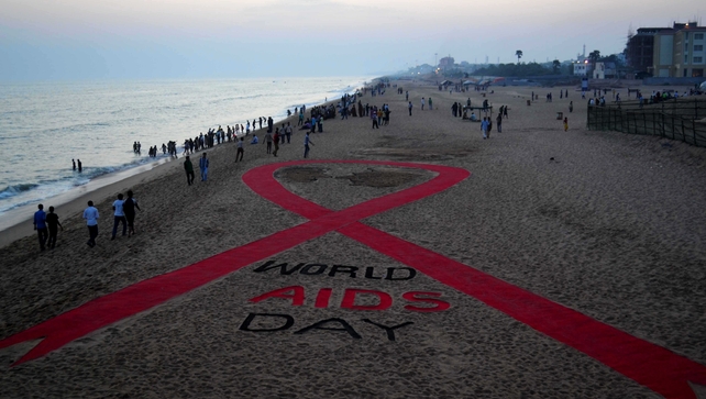 Indian residents walk past a sand sculpture incorporating what is aimed to be the worlds longest red ribbon created by sand artist Sudarsan Pattnaik at Puri beach, some 65 kms from Bhubaneswar