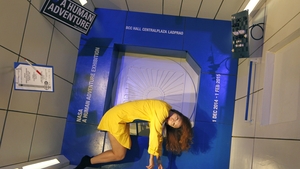 A visitor poses for a photograph in the gravity experimental module at the 'NASA - A Human Adventure' space exhibition in Bangkok, Thailand