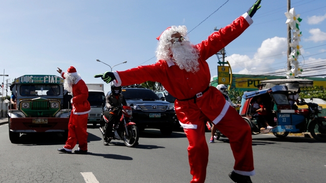 Filipino security officers wearing Santa Claus costumes direct the traffic in front of a shopping mall in Paranaque city, south of Manila