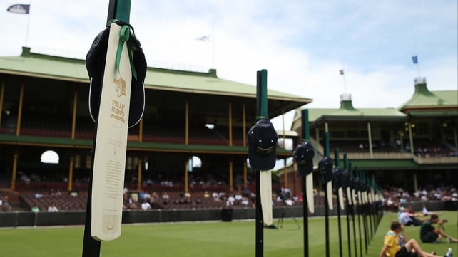 63 cricket bats with Phillip Hughes' milestones are displayed as people gather to watch the funeral at the Sydney Cricket Ground