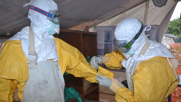 Health workers check each other's protective clothing at a treatment centre in Guinea