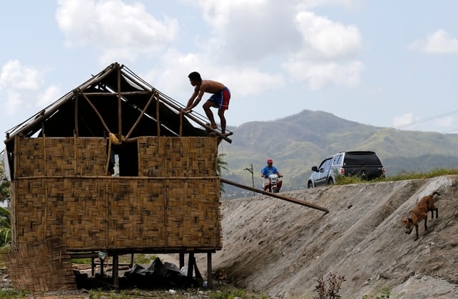 Filipino typhoon victim Alfredo dela Pena fixes the roof of his damaged house in the Typhoon Hagupit hit town of Quinapondan, Samar Island, Philippines