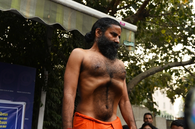 Indian yoga guru, Baba Ramdev demonstrates a yoga exercise to the media during a press conference on the declaration of a 'yoga day' in New Delhi