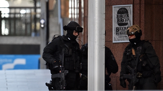 Armed police stand near a café in the central business district