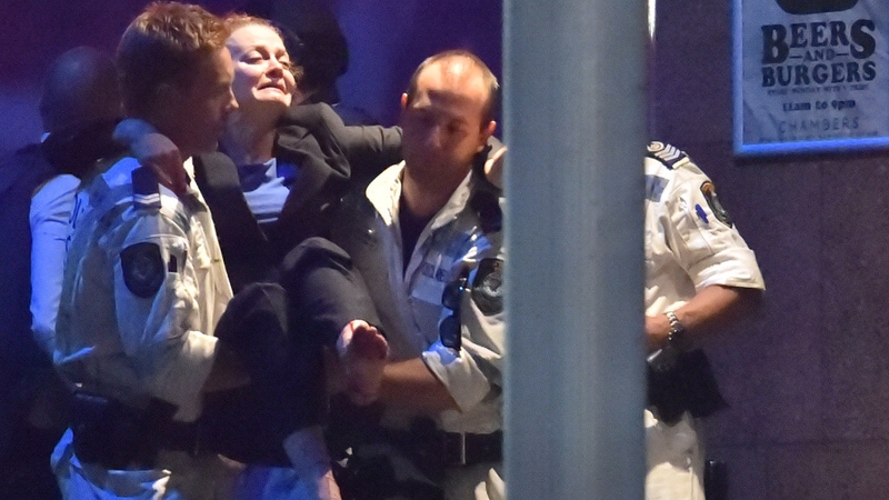 Rescue teams carry a woman out of the Lindt Café