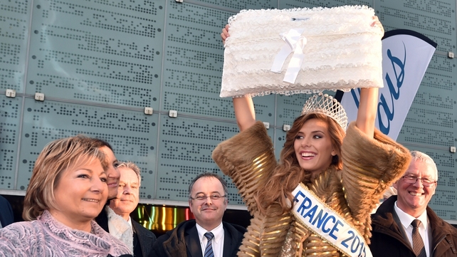Miss France 2015 Camille Cerf holds up a piece of lace in front of the International Centre of Lace and Fashion in Calais