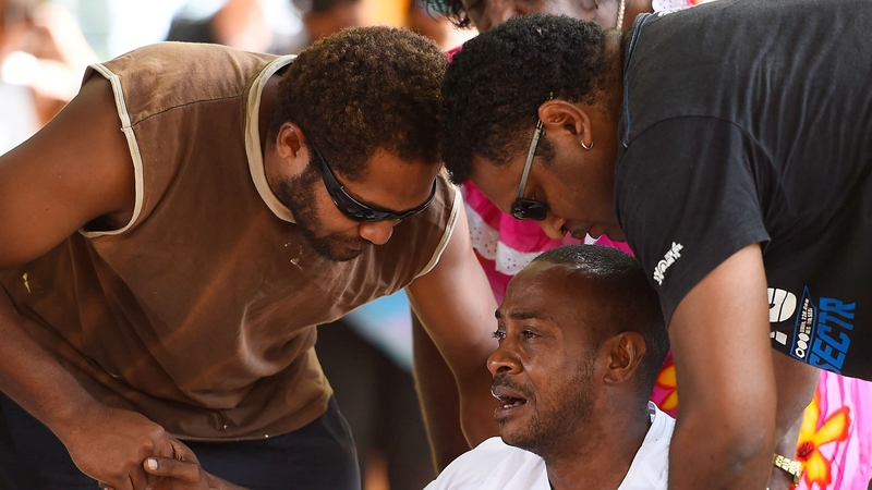 Family members mourn at a memorial which is located in the park next the scene of the crime