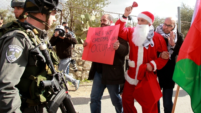 A Palestinian protester dressed as Santa Claus argues with an Israeli border policeman in Palestine