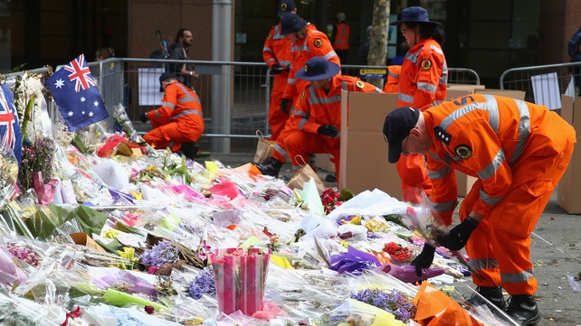 Volunteers clear away floral tributes to those killed in last week’s hostage siege at Martin Place in Sydney