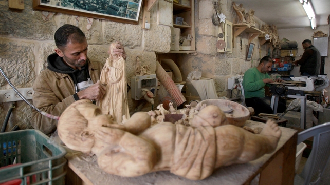 A Palestinian wood sculptor works on an olive wood figure for a Nativity scene at his workshop in Bethlehem