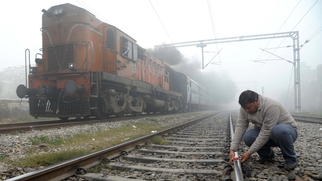An Indian Railways employee places 'fog signals' on a railway track as a train passes in dense fog at a railway station in Amritsar