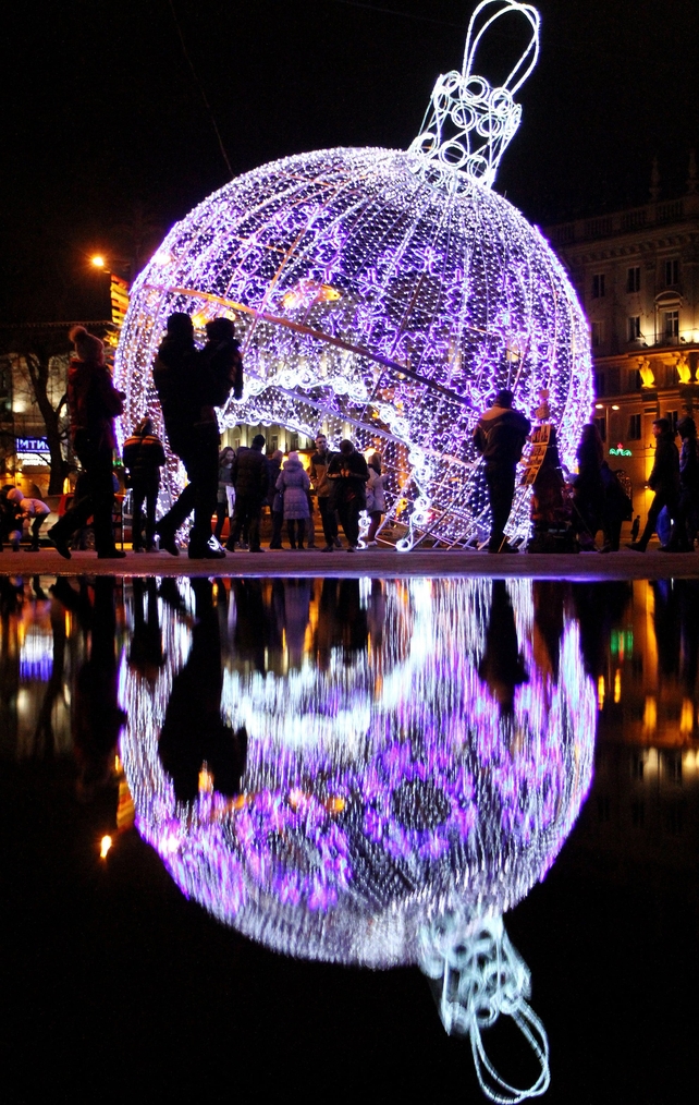 People walk past a giant illuminated Christmas tree bauble in central Minsk