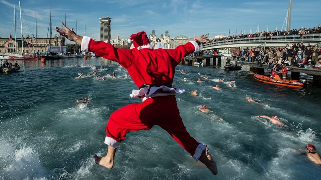 A competitor in Christmas fancy dress jumps into the sea during the 105th Barcelona Traditional Christmas Swimming Cup at the Old Harbour of Barcelona