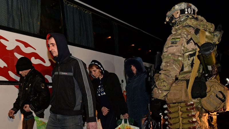 Prisoners from the self-proclaimed 'People's Republic of Donetsk' walk as a Ukrainian soldier stands guard prior to a prisoner exchange