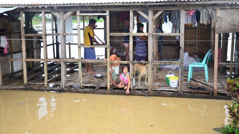 A Filipino family inside their damaged house surrounded by floodwaters due to tropical storm Jangmi in Ormoc town, Leyte province