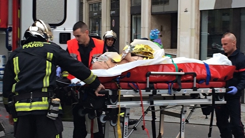 Firefighters carry an injured man on a stretcher in front of the offices of French satirical weekly Charlie Hebdo