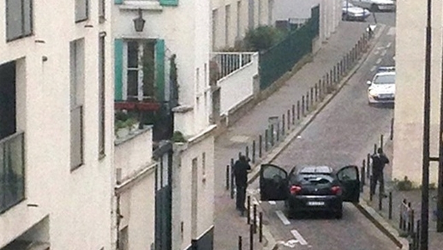 Armed gunmen face police officers close to the newspaper's HQ
