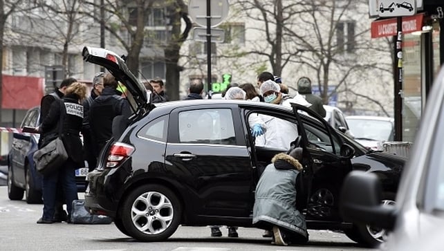 Police officers and forensic experts examine the car used by the gunmen