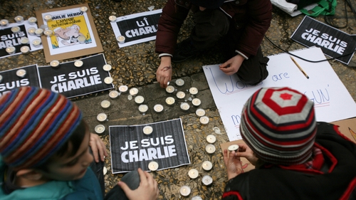 Children light candles next to placards reading in French 'I am Charlie' and 'Nicosia is Charlie' during a gathering at Eleftheria Square in central Nicosia, Cyprus