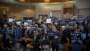 People hold signs while attending a ceremony honouring the victims of the shootings in France in Jerusalem