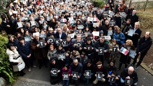 In Tokyo French residents stand underneath the French national flag with a black ribbon as they hold signs