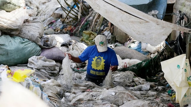 A Filipino scavenger sorts out recyclable materials before a feast of 'pagpag' (recycled food) in eastern Manila