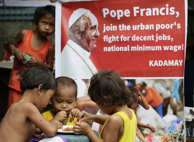 Children of Filipino food scavengers eat a "pagpag" (recycled food) meal from a dump site ahead of Pope Francis' visit to the Philippines