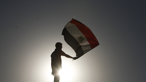 An Egyptian protester waves his national flag at sunset during a demonstration in Cairo's landmark Tahrir Square