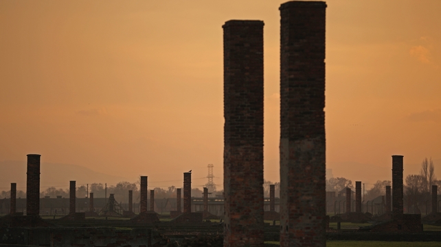 The sun rises over chimneys and the remains of detention blocks at the Auschwitz II Berkenau