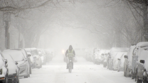 A man cycles down a street in Brooklyn as the storm begins