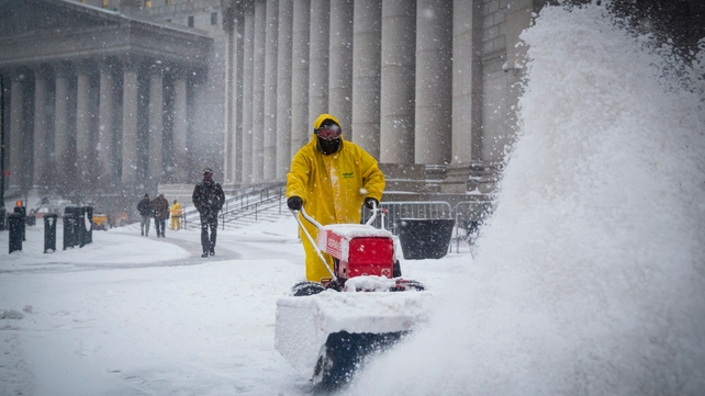 A worker clears snow from near Foley Square in New York