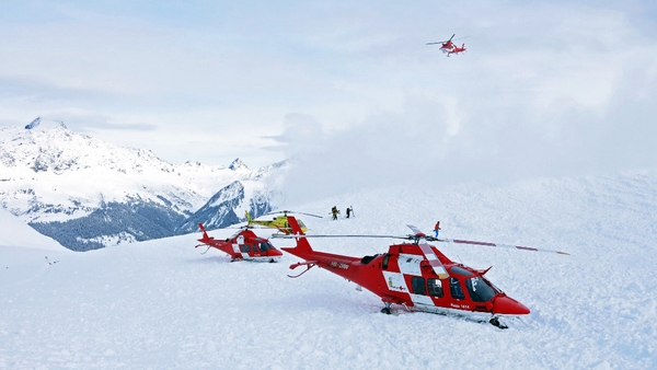 Rescue helicopters and rescue workers on duty after an avalanche on the Piz Vilan mountain